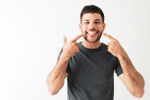 a man points to the results of his cosmetic dentistry procedure